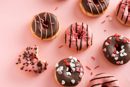A top view of chocolate and pink donuts messily arranged on a pink surface