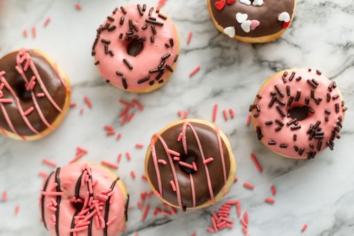 A top view of chocolate and pink donuts messily arranged on a marble surface