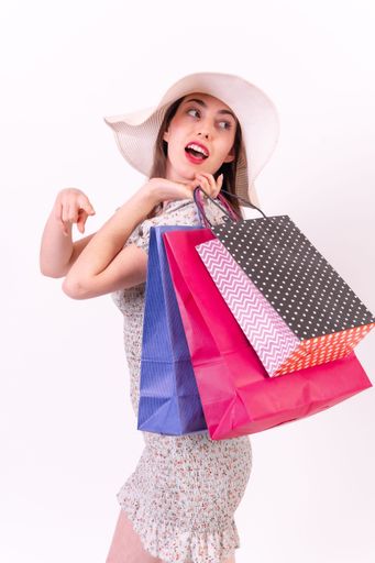 A cheerful Caucasian female demonstrating her shopping bags on white background