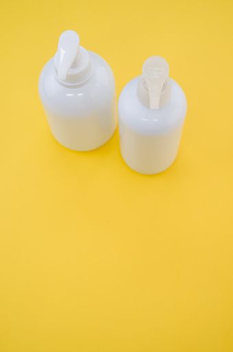 A ve of plastic bottles with pumps on a yellow surface under the lights