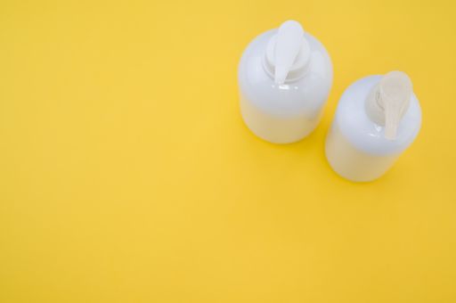 A high angle shot of plastic bottles with pumps on a yellow surface under the lights
