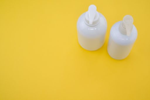 A high angle shot of plastic bottles with pumps on a yellow surface under the lights