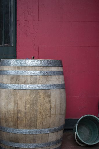 A vertical shot of a wooden barrel in front of a pink wall