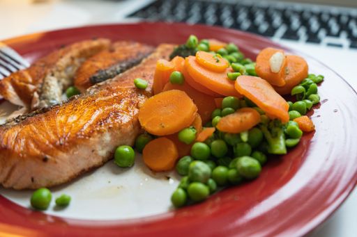 A closeup shot of a plate with carrots green beans and fish