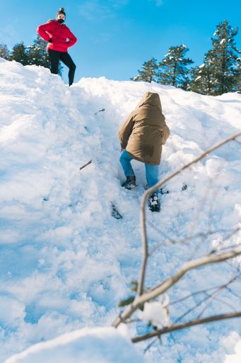 A vertical shot of a woman in a red jacket on top of a snowy hill