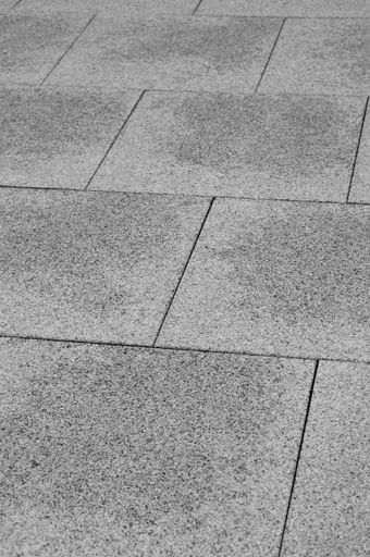 A vertical high angle shot of a cobblestone ground with grey square tiles
