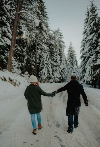 A Beautiful view of a couple wearing warm clothes holding hands and having fun at the snow park