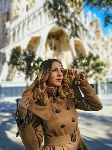 A vertical shot of a fashionable lady with ombre hair wearing a beige trench coat outdoors