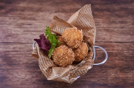 A top view of homemade ham croquettes in a bucket on rustic wooden background