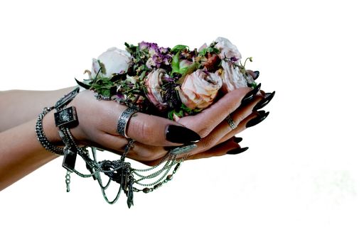A closeup shot of a woman's hand with manicure and ethnic tribal jewelry offering scented mixture of dried flowers