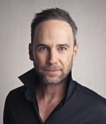 A portrait of a handsome adult man with gray eyes wearing a black shirt