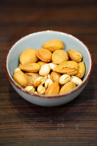 A vertical shot of a bowl of pistachios and almonds in shells on the table