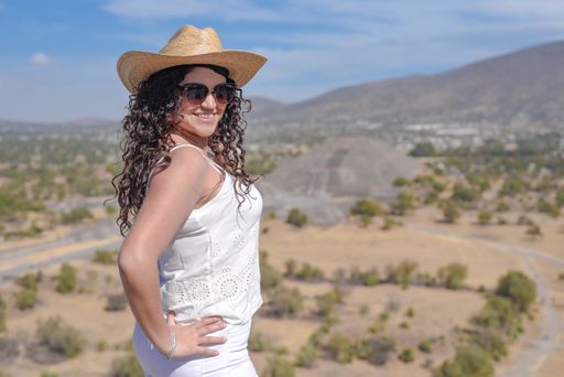 A portrait of a smiling Hispanic female wearing white clothes and a hat