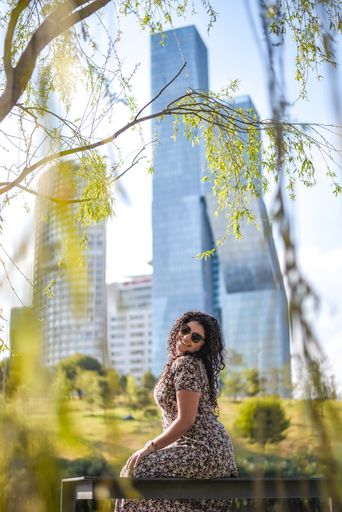 A vertical shot of a young Hispanic female sitting on a bench in a park