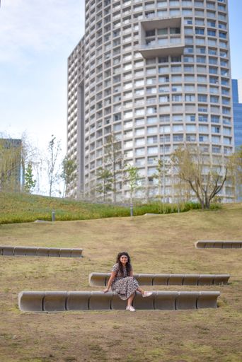 A vertical shot of a young Hispanic female sitting on a bench in the park
