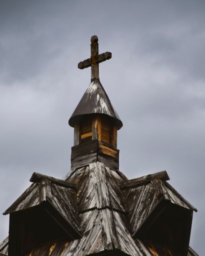 A vertical shot of a top part of a church covered in snow under a cloudy sky.