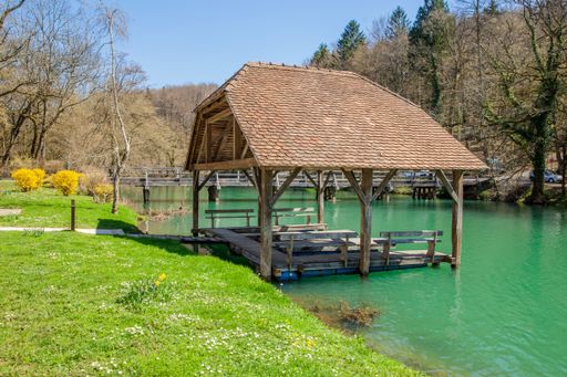 A wooden pavilion situated in the turquoise river during the daytime