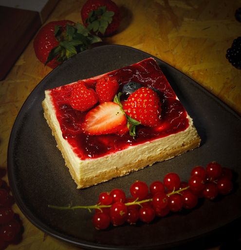 A beautiful view of Cheesecake with strawberry on the black plate
