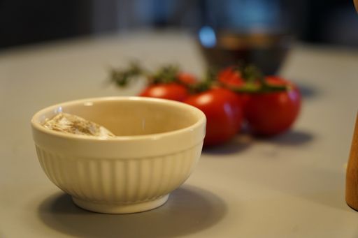 A selective focus shot of food in a bowl with cherry tomatos on the side