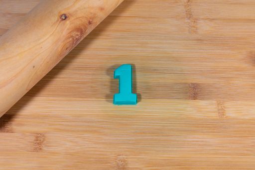 A top view of the number "one" made from blue plasticine on a wooden table