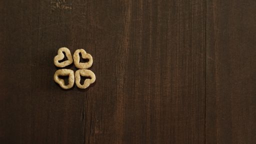 A top view of four heart-shaped cereal pieces arranged on the left side of a wooden surface with a copy space