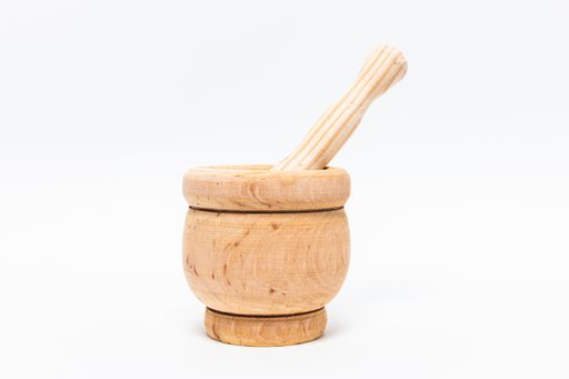 A closeup shot of a wooden mortar for grinding various culinary spices isolated on a white background