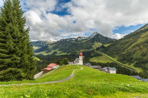 An idyllic landscape showing a range of jagged mountains and a small village in Vorarlberg, Austria