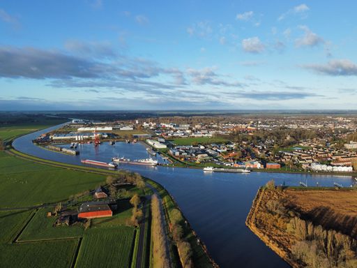 An aerial shot of a canal and boats in a small city under the blue sky and clouds