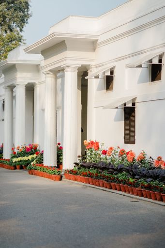 A vertical shot of a white building facade decorated with flowers in pots