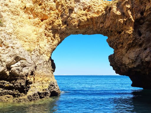 A scenic view of the rocky coastline of Portugal, featuring crystal clear blue waters and a stunning shoreline