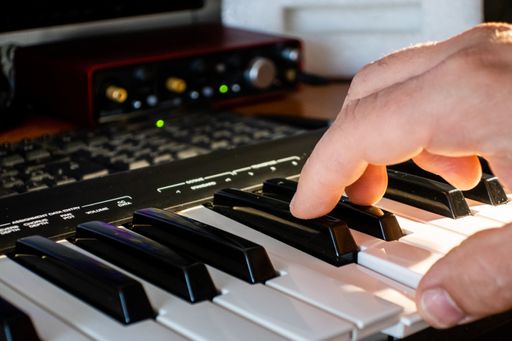 A closeup shot of hands of a male musician playing a synthesizer at a sound recording studio