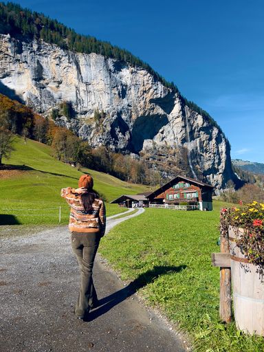 A vertical shot of a female standing against Staubbach Falls in Lauterbrunnen, Switzerland