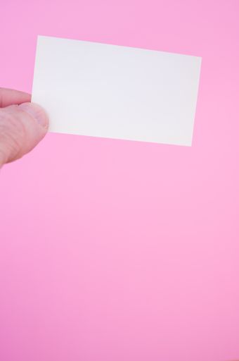 A vertical isolated shot of the blank white card on a pink background- free space for text