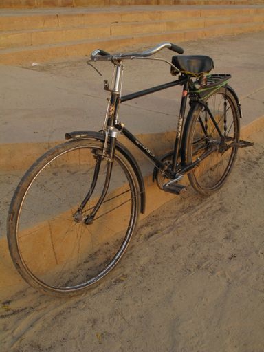 A vertical shot of a bicycle leaned against a stair on the sidewalk