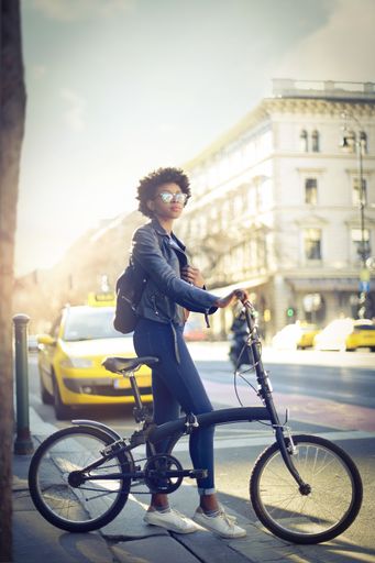A shallow focus of a young African woman with short curly hair riding a bicycle outdoors
