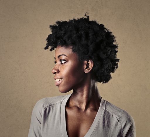 A portrait of the side profile of a young African female with short curly hair aga