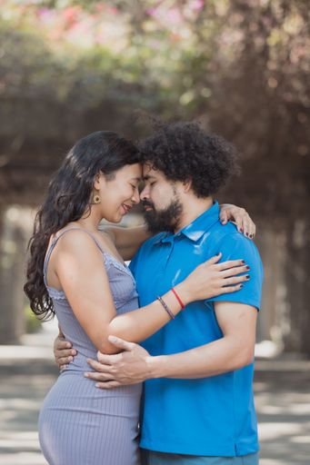 A happy couple smiling and hugging each other under the trees