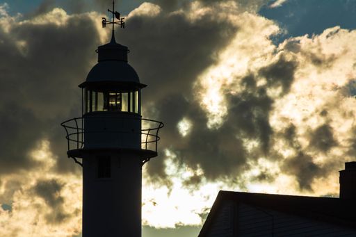 Silhouette of Lobster Cove Head Lighthouse with Backlit Clouds, Newfoundland and Labrador, Canada.