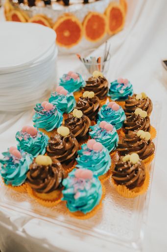 A vertical shot of blue-black decorated cupcakes on the glass plate on the blurred background