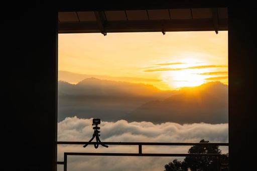 A person stands alone against a backdrop of a stunning sunset, looking out at the horizon from their vantage point near the railing