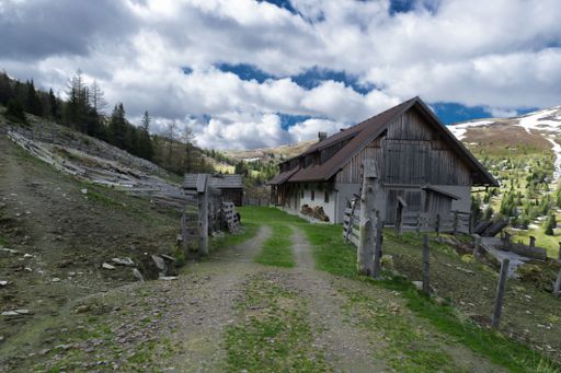 A single old house in the rural area under the white cloudy sky.