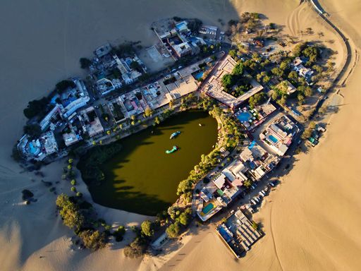 A drone view of the Huacachina in a desert on a sunny day in Peru