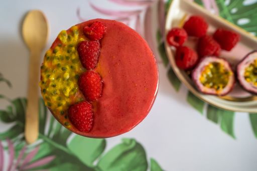 A top view of a raspberry and passionfruit smoothie bowl on a white table