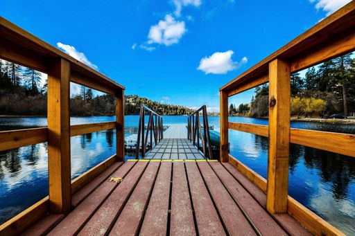 A beautiful view of a wooden platform over a lake under a blue sky with clouds.