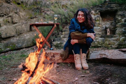 A young woman sitting next to a fire with closed eyes during a winter picnic