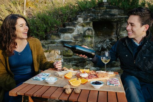 A loving couple having an outdoor lunch in the garden and tasting wine