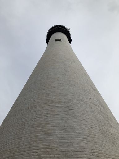 A low angle shot of a lighthouse under a cloudy sky