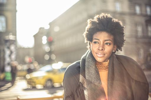 A shallow focus of a young African woman with short curly hair posing under the bright sunlight