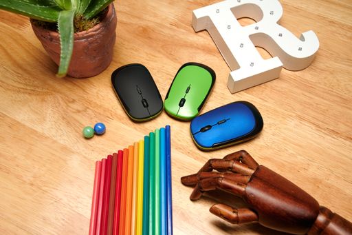 A top view of multi-colored pencils, computer mouses with an articulated wooden hand