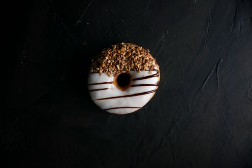 A top view of a glazed donut with nuts